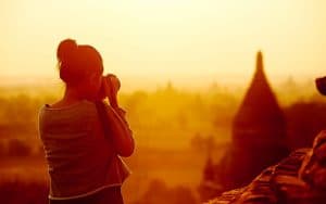 Silhouette of a traveler photographing temples at sunset.